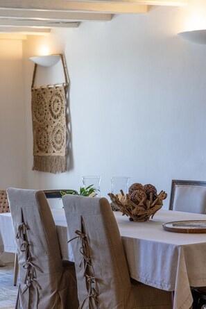 Zona pranzo con tavolo apparecchiato per quattro persone, con un centrotavola intrecciato, un arazzo macramè e un design semplice ed elegante.