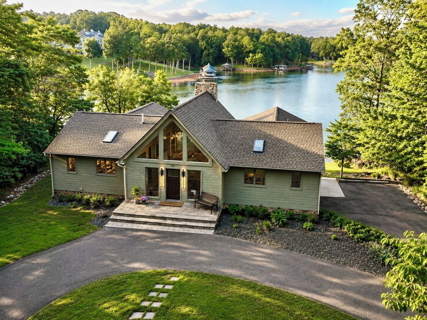 A two-story house with a stone chimney, a front porch, and a view of a lake.