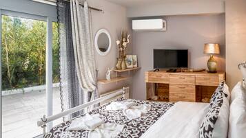 Een slaapkamer met een groot bed, een televisie, een dressoir en een raam met uitzicht op groen.