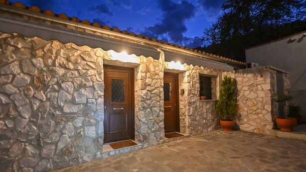 Un edificio in pietra con due porte in legno, una piccola finestra e vasi di piante.