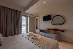 Quarto de hotel moderno com uma cama grande, televisão de tela plana, espelho e porta de vidro deslizante para uma varanda.