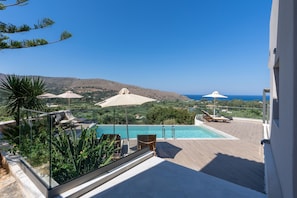 A poolside area with a view of the sea and hills. - Villa Dorothea in Georgioupoli (Georgioupoli)