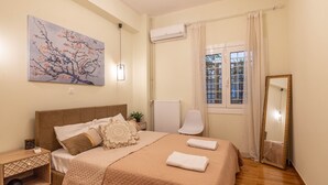 A neatly arranged bedroom with a bed, bedside table, and a wall-mounted air conditioner. - Prime 2BR Apartment next to Kallimarmaro Stadium (Athens)