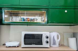 A microwave, a kettle, and a glass display cabinet with various items. - Sunny 1bd apartment just 1minute to Acropolis (Athina)