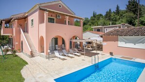 Ein zweistöckiges Gebäude mit Swimmingpool, Außenbereich zum Sitzen und einer Treppe, die zu der oberen Etage führt.