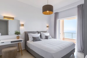 Ein modernes Schlafzimmer mit einem großen Bett, einem Schreibtisch und Meerblick.