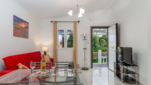 Uma sala de estar moderna com uma mesa de jantar de vidro, sofá vermelho e um rack para TV.