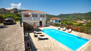 Eine moderne Villa mit Swimmingpool, Steinterrasse und Blick auf die umliegende Landschaft.