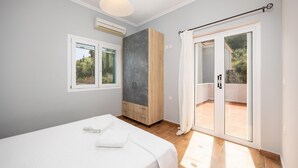 Een slaapkamer met een bed, een kledingkast, een raam en een schuifdeur naar buiten.