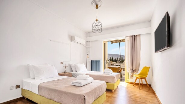 Hotellihuone, jossa on kaksi sänkyä, televisio, tuoli ja näkymä ulos.