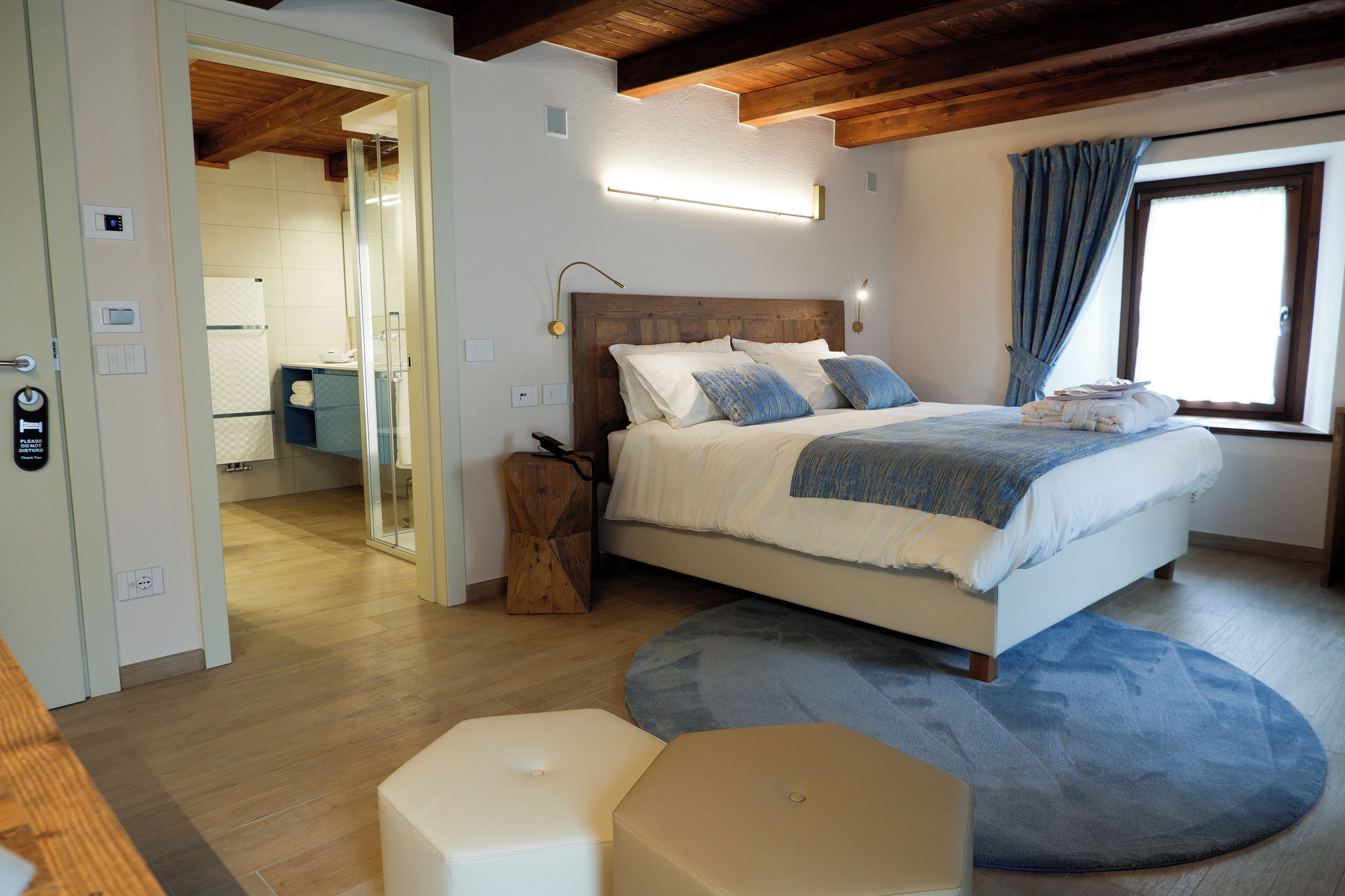 A bedroom with a bed, bedside tables, a mirror, and a window with curtains.