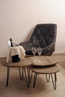 Un sillón de cuero oscuro, una mesa de centro de madera con dos copas de vino, y una botella de champán sobre una mesita.