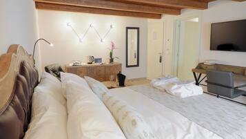 A bedroom with a large bed, a wooden headboard, a bedside table with a lamp, a dresser, a mirror, and a TV.
