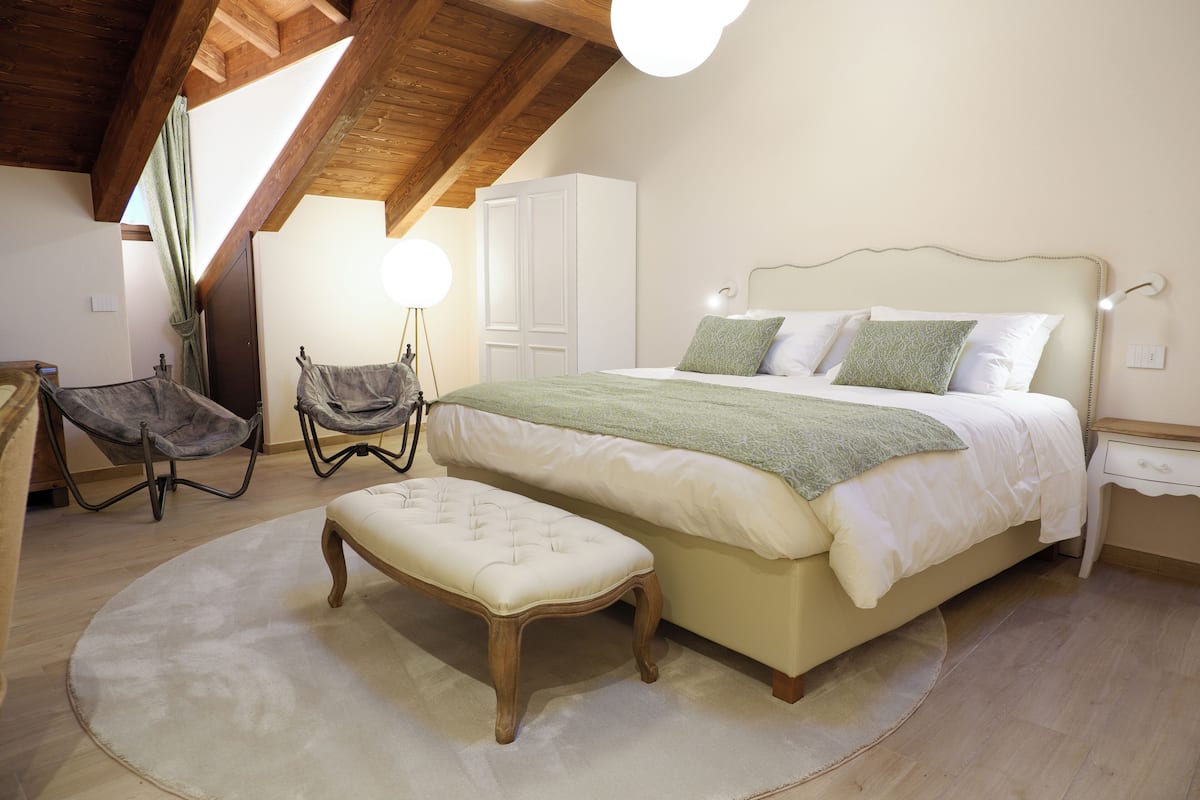 Un dormitorio con cama, banco, armario y silla.