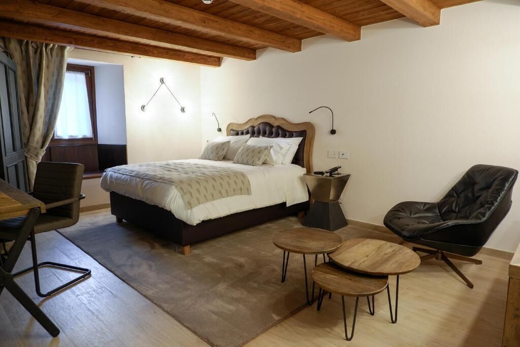 Een slaapkamer met een groot bed, een bureau, twee stoelen en een kleine tafel.