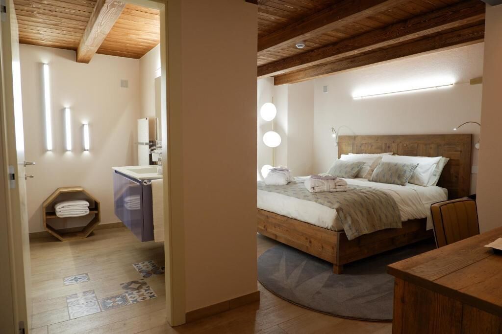 Een slaapkamer met een houten hoofdbord, een bed met wit beddengoed, een nachtkastje en een houten nachttafeltje.