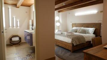 Een slaapkamer met een houten hoofdbord, een bed met wit beddengoed, een nachtkastje en een houten nachttafeltje.