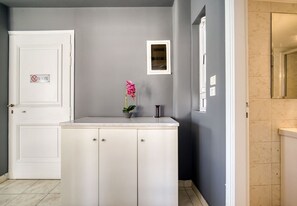 A bathroom with a white sink, a mirror, and a door with a 'No Smoking' sign. - Sunny penthouse in Koukaki - Next to  Acropolis (Athina)