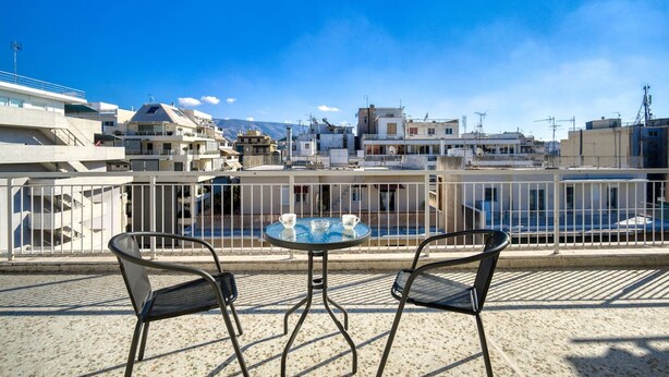 A rooftop terrace with a table and chairs, overlooking a cityscape with buildings and a clear blue sky. - Sunny penthouse in Koukaki - Next to  Acropolis (Athina)