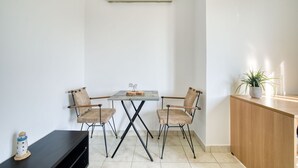 A small, modern room with a table and four chairs, a wooden cabinet, and a potted plant. - Sunny penthouse in Koukaki - Next to  Acropolis (Athina)