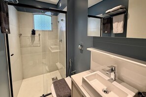 Ein modernes Badezimmer mit einer Duschkabine aus Glas, einem Waschbecken und einem Spiegel darüber.