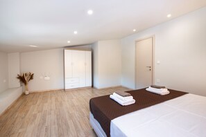 A modern bedroom with a large bed, a wardrobe, and a door. - Casa di Mina's in Chania (Metochi Siriliou)
