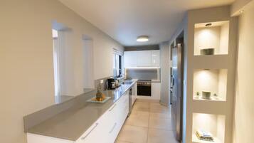 Una cocina moderna con armarios blancos, una isla grande y estanterías empotradas.
