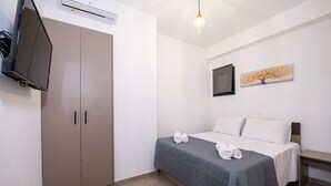 Ett hotellrum med en säng, en garderob, en platt-TV och en tavla på väggen.