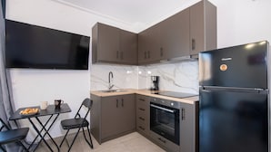 Uma cozinha compacta com forno embutido, geladeira e pequena área de refeições com mesa e cadeiras.