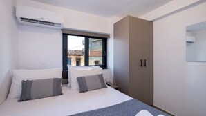 Ein Schlafzimmer mit einem Bett, Kissen, einem Kleiderschrank und einer Klimaanlage.