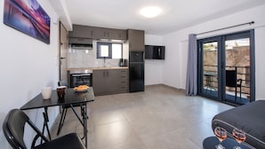 Eine moderne Küche mit Essbereich, einem Flachbildfernseher und einem Balkon mit Tisch und Stühlen.