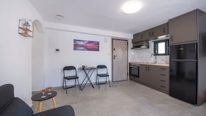 Eine moderne Küche mit Einbauofen, einem schwarzen Kühlschrank und einem Essbereich mit einem kleinen Tisch und Stühlen.