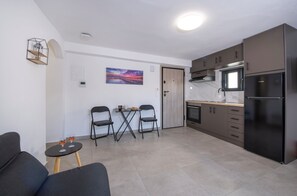 Eine moderne Küche mit Einbauofen, einem schwarzen Kühlschrank und einem Essbereich mit kleinem Tisch und zwei Stühlen.
