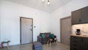 Um espaço compacto com cozinha compacta, um sofá, uma mesa de centro e uma pequena mesa com um vaso.