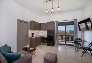 A modern kitchen with a dining area, a sofa, and a TV. - Halepa Apartment in Chania Olivia 6 (Chania)