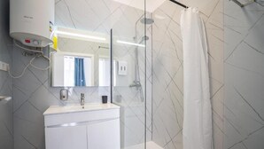 A modern bathroom with a glass-enclosed shower, a white sink, and a mirror above it. - Zarco Suites by Sé Funchal (Funchal)