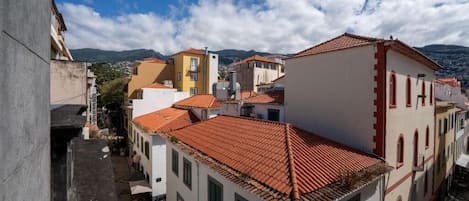 Une rue étroite bordée d’immeubles aux toits recouverts de tuiles rouges et aux murs blancs, typiques de l’architecture méditerranéenne.