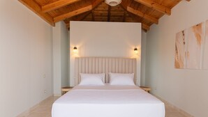 Une chambre avec un grand lit, des poutres apparentes en bois au plafond et deux lampes fixées au mur.