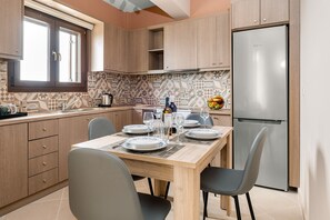 Une cuisine moderne avec des meubles en bois, un réfrigérateur en acier inoxydable et une table à manger pour quatre personnes.