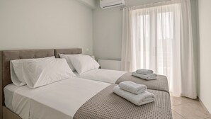 A hotel room with two beds, white bedding, a grey headboard, and a window with sheer curtains. - Apartment Eliana - 3 brms - 1st floor - Building B (Fokata)