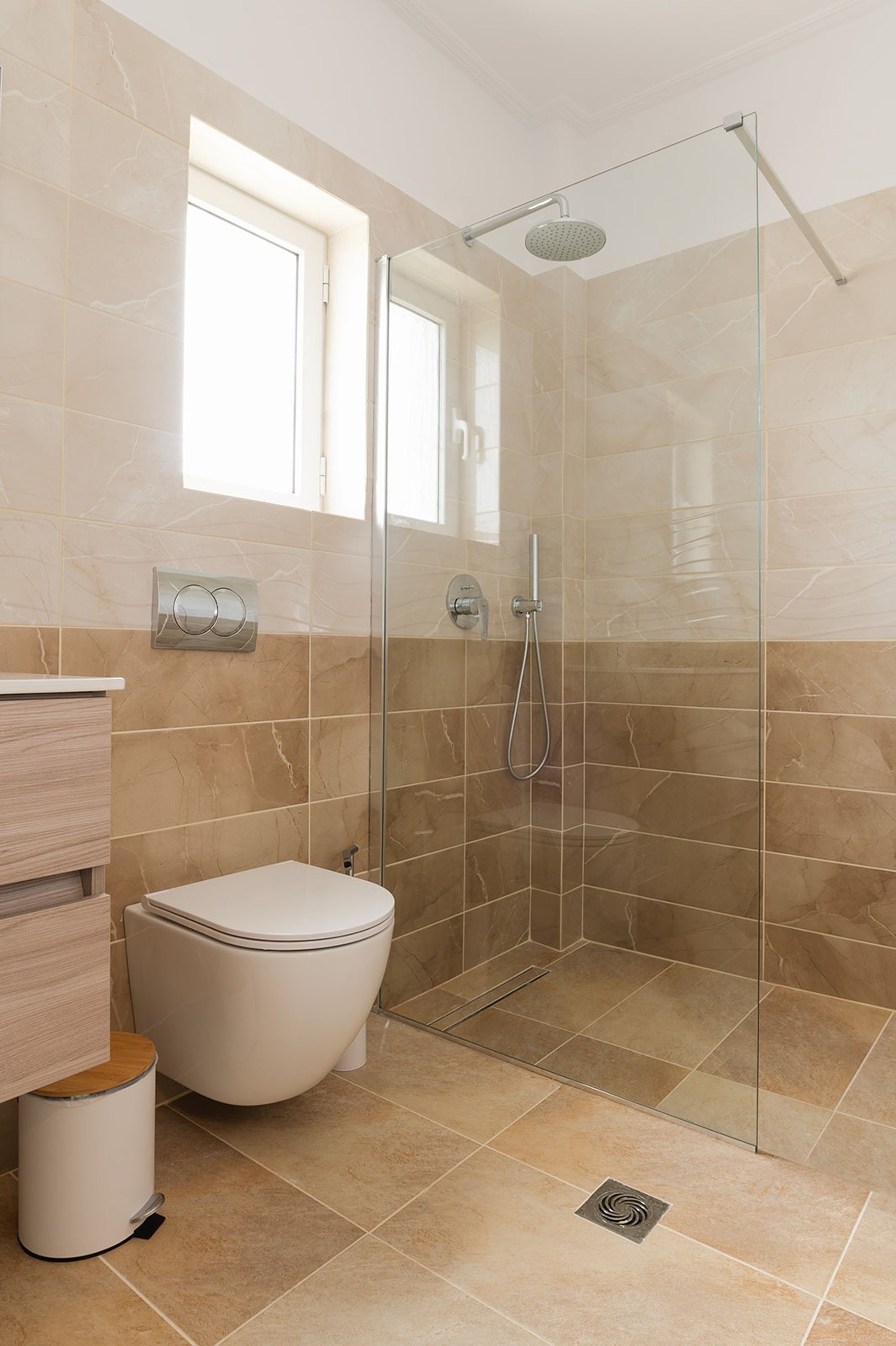 A bathroom with a glass-enclosed shower, a toilet, and a vanity with a mirror.