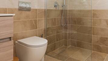 A bathroom with a glass-enclosed shower, a toilet, and a vanity with a mirror.