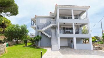 A multi-story residential building with a stone facade, a central staircase, and a balcony on the upper floor.