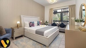 Une chambre d’hôtel avec un grand lit, une table de chevet avec une lampe, un canapé, une commode et un grand miroir.
