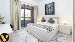Une chambre moderne avec un lit, des tables de chevet, une fenêtre avec des rideaux et une œuvre d’art accrochée au mur.