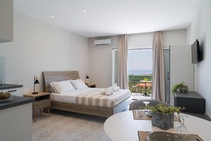 A modern bedroom with a bed, bedside tables, a TV, and a balcony with a view. - 206 - Deluxe Queen Studio with sea view (Moussata)