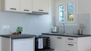 Een moderne keuken met witte kasten, een inbouwvaatwasser en een raam met uitzicht op groen.