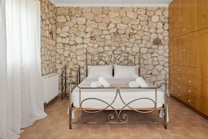 Ein Bett mit einer Steinwand im Hintergrund, einem Holzschrank und einem Heizkörper.