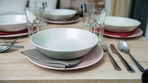 A dining table set with plates, bowls, glasses, and cutlery. - Standard Triple Room (Travliata)