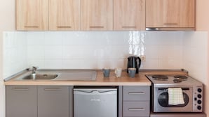 A modern kitchen with wooden cabinets, a stainless steel sink, a dishwasher, a coffee maker, and a built-in oven. - Standard Triple Room (Travliata)